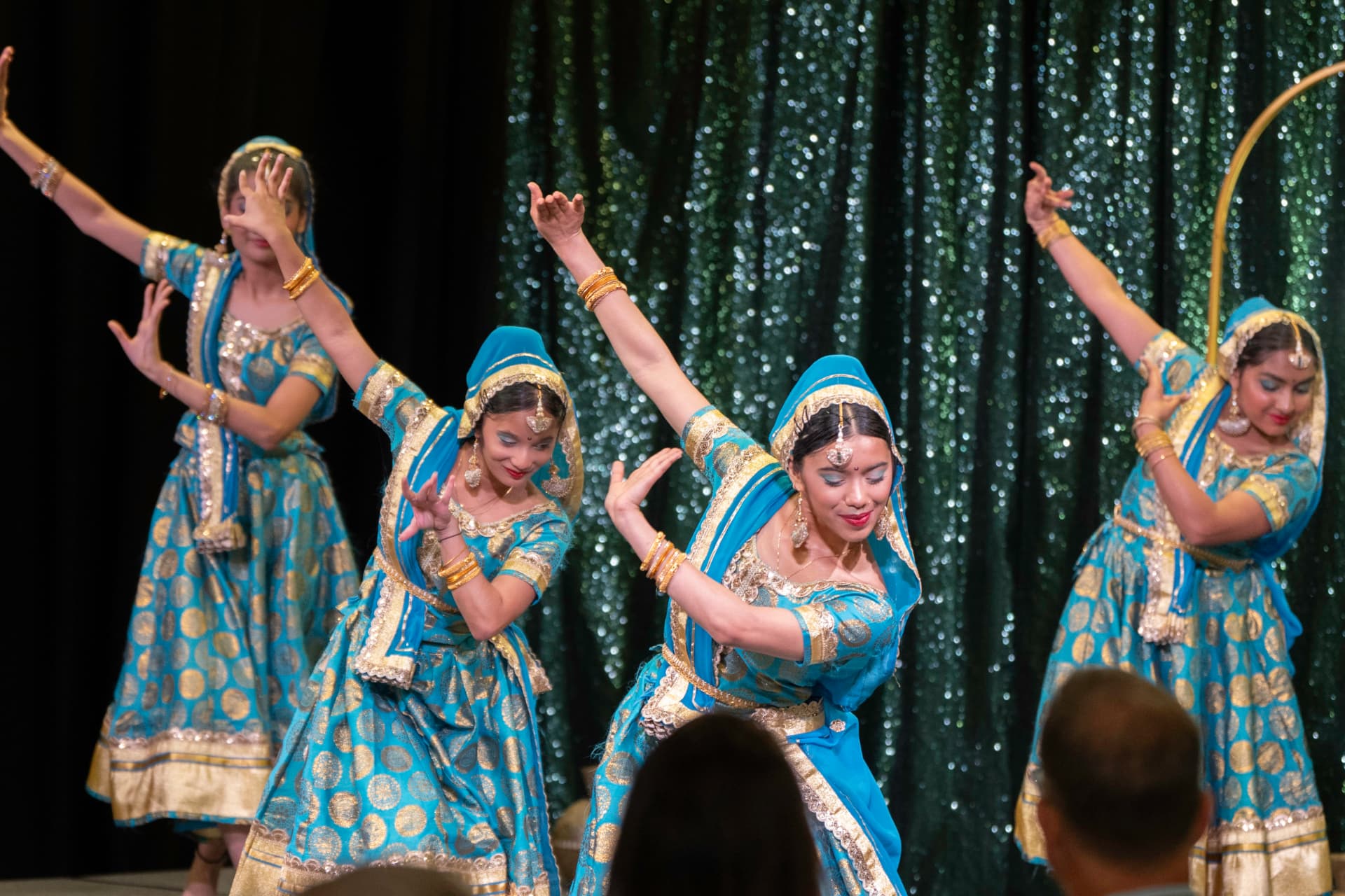 Performers in blue and gold traditional costumes dance on stage at Taste of India 2026