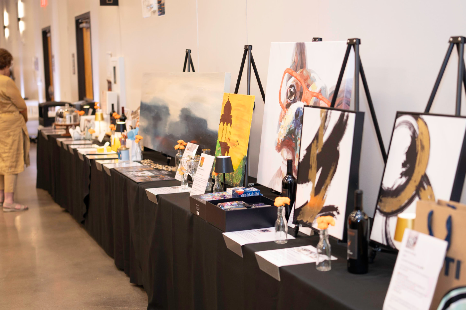 Silent auction tables displaying artwork and prizes at Taste of India 2026